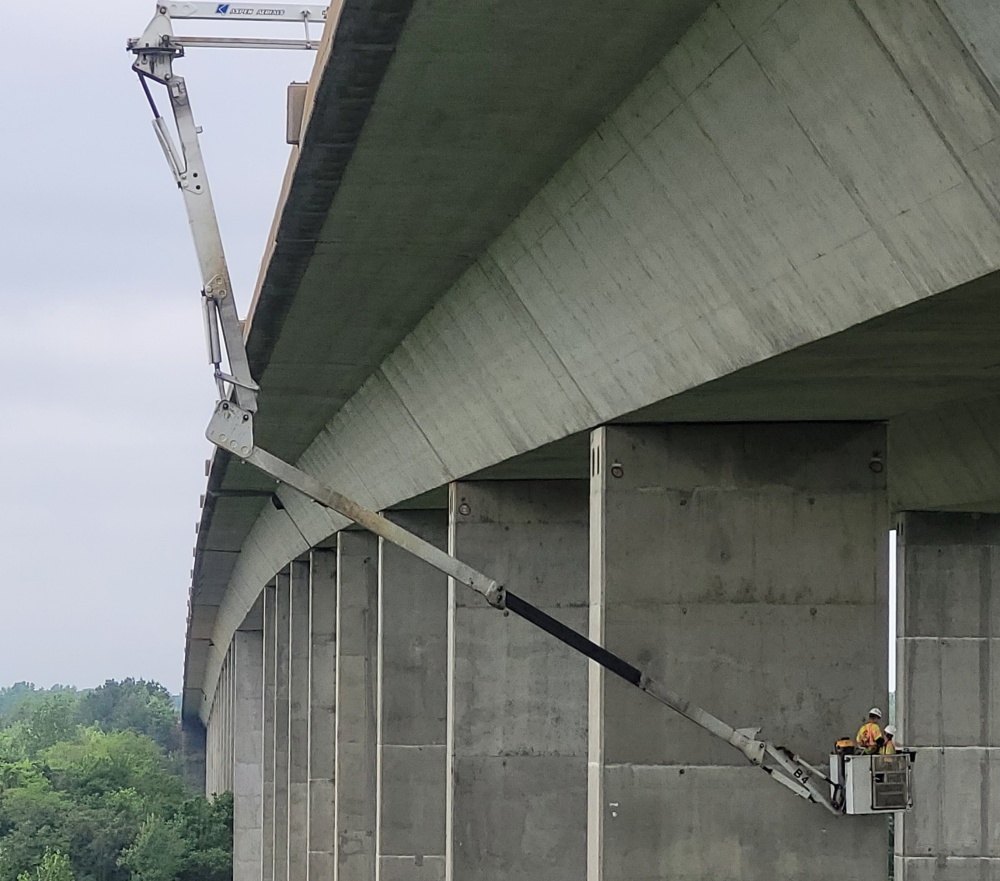 Two engineering performing a bridge pier inspection using a Under Bridge Inspection Unit (UBIU).