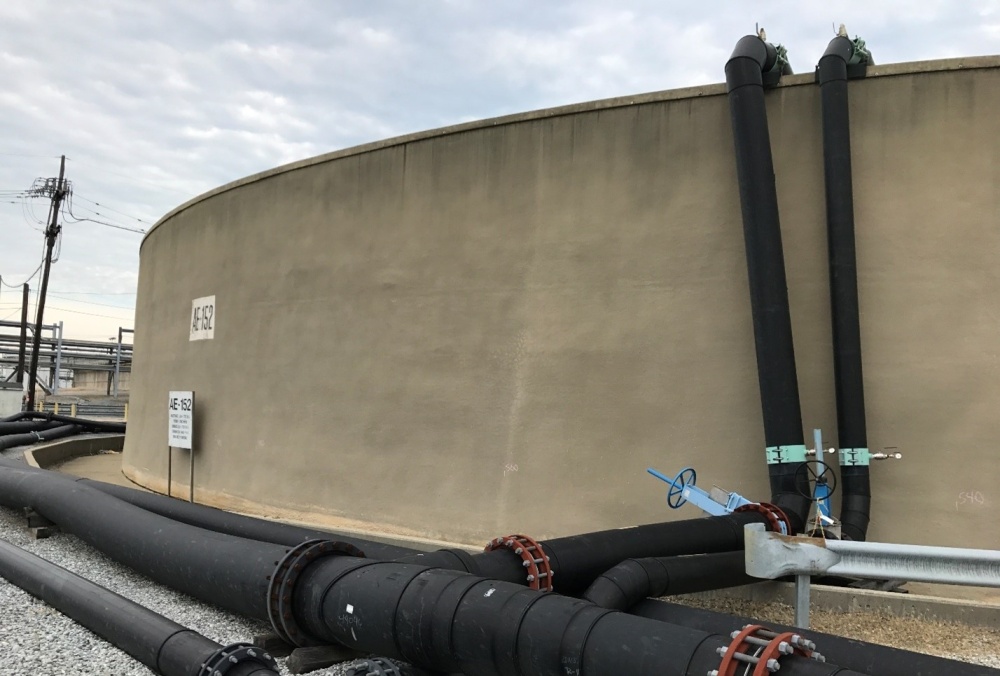 Concrete Tank with black pipes with valves running vertically and horizontally alongside it.